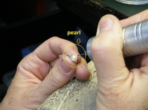 Holding a pearl with a masking tape "handle" to drill it.